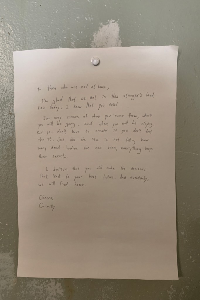 A note nailed on the wall that reads, "To those who are not at home, I'm glad that we met in this stranger's land. From today, I know that you exist. I am very curious of where you came from, where you will be going, and where you will be staying. But you don't have to answer if you don't feel like it. Just like the sea is not telling how many dead bodies she has seen, everything keeps their secrets. I believe that you will make the decisions that lead to your best future. And eventully, we will find home. Cheers, Carmilly"